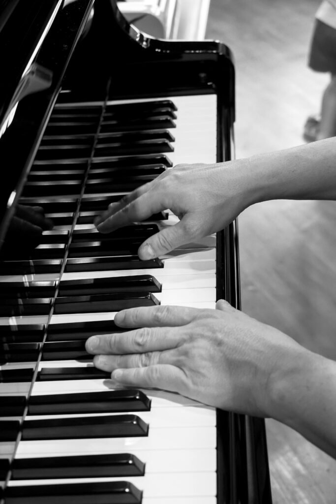 Elegant black and white photo of hands playing a piano, showcasing musical talent.