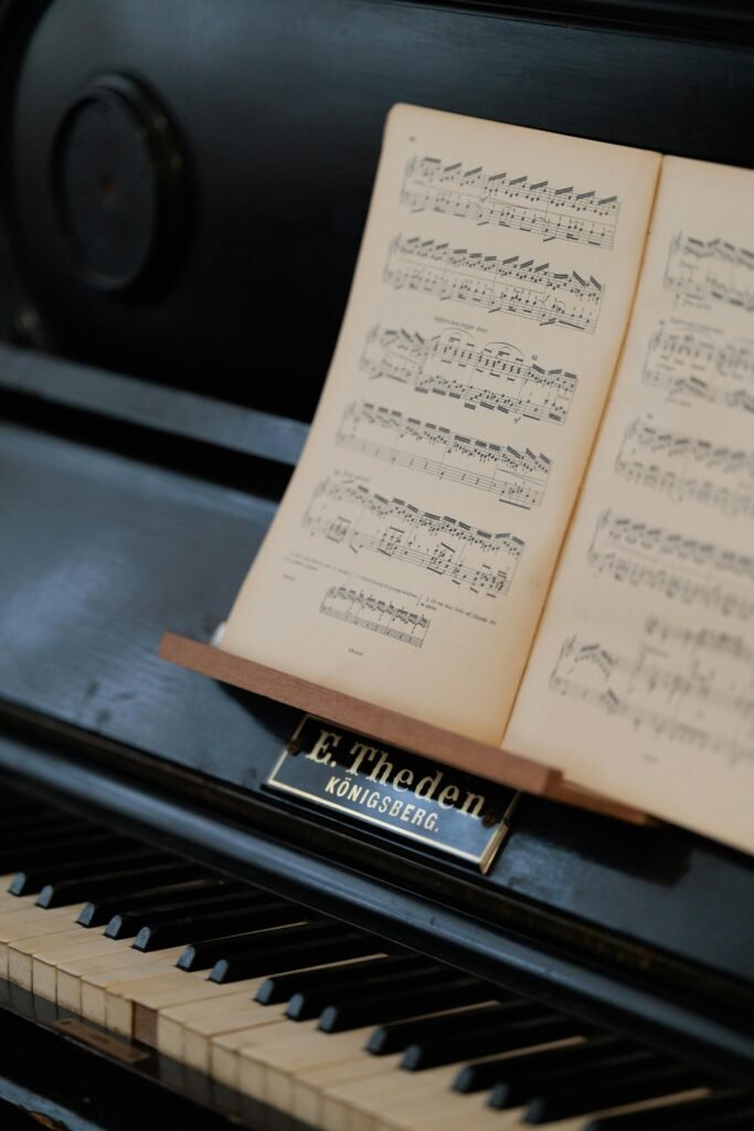 Close-up of a classic upright piano with open sheet music and brand label "E. Theden, Königsberg."